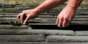 An image of a person carefully laying slate roofing tiles.