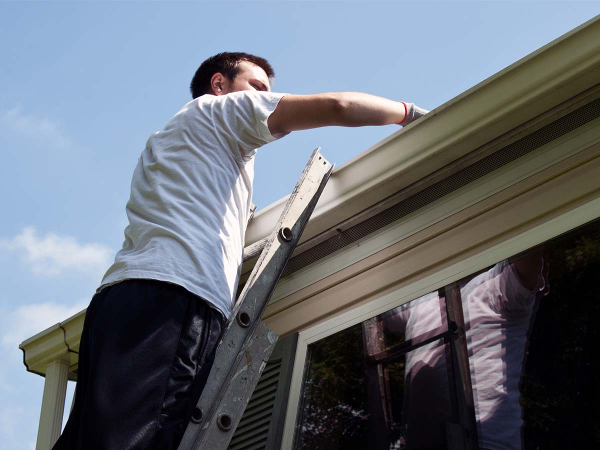 :Man on roof preparing to instal a gutter.