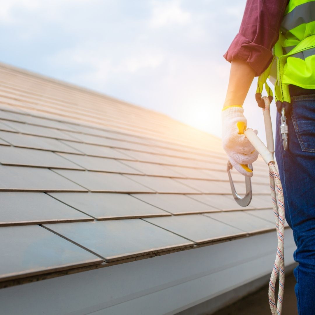 A roofing contractor stands at the edge of a roof