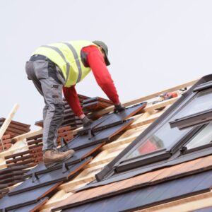 man climbing up roof while installing new shingles